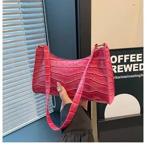 Détail de la texture croco rose et de la boucle dorée sur le sac baguette chic
