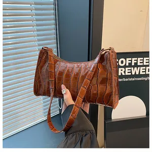 Gros plan sur la texture en cuir crocodile marron et les détails du sac à bandoulière