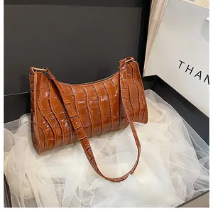 Détail du sac à bandoulière marron motif crocodile sur une boîte cadeau élégante
