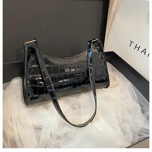 Détail d'un sac à main noir motif crocodile avec boucle en métal doré élégant