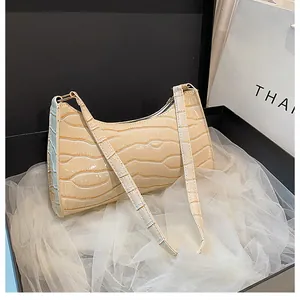 Détail du sac croissant embossé crocodile dans une boîte cadeau noire et tulle blanc