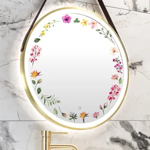 Gros plan d'un miroir de salle de bain LED doré avec motifs floraux et capteur tactile