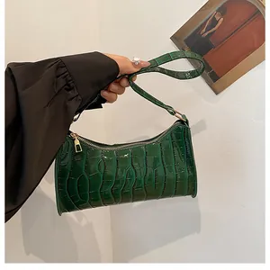 Détails du motif crocodile vert foncé sur un sac baguette en similicuir brillant