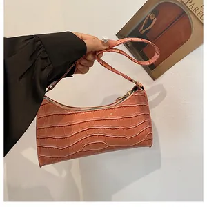 Détail du sac baguette orange-rose avec motif crocodile, texture similicuir et lanière