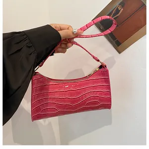 Détail de la texture crocodile fuchsia sur sac baguette chic porté à l'épaule pour femme