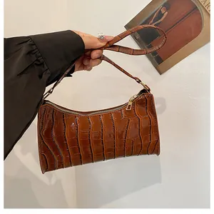 Détail du motif crocodile marron brillant sur le sac baguette avec fermeture dorée