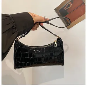Détail du sac à main noir motif crocodile avec fermeture éclair dorée élégante