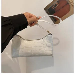 Détail du sac baguette blanc à motif crocodile avec fermeture éclair dorée chic