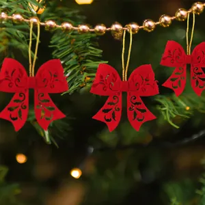 Red felt Christmas tree bow ornaments with intricate hollow floral patterns and gold strings