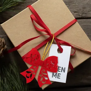 Close-up of kraft gift box with red felt bow and OPEN ME tag on dark wood background
