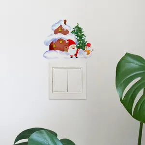 Détail d'autocollants Père Noël et bonhomme de neige autour d'un interrupteur mural
