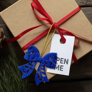 Close-up of a rustic gift box with red ribbon and blue felt bow on a festive wooden table