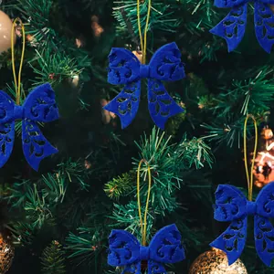 Blue felt Christmas bow ornaments with laser-cut patterns on a green festive tree