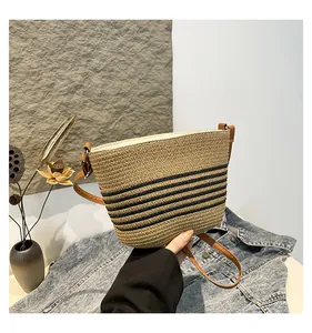 Detail of hand-woven straw bucket bag with black stripes and brown leather strap