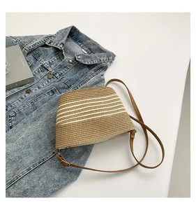 Close-up of woven straw crossbody bag texture with adjustable brown leather shoulder strap