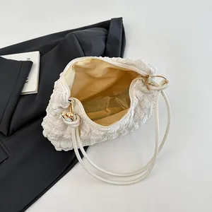 Sac sous le bras blanc à texture bulle avec détails dorés sur un blazer noir