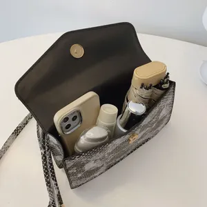 Contrast snakeskin crossbody bag with magnetic buckle showing internal storage capacity