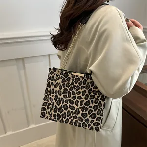 Sac fourre-tout à imprimé léopard avec chaîne dorée porté par un mannequin en trench-coat