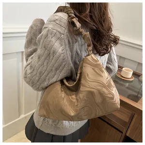Detail of ruched cloud strap shoulder bag with marble texture styled with grey sweater