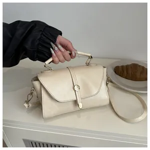 Detail of cream leather handbag with gold circular buckle and adjustable shoulder strap