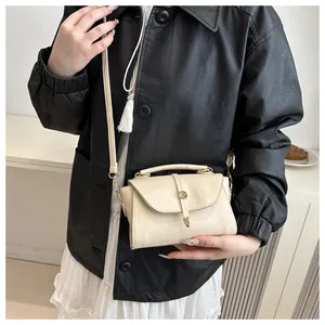 Close-up of a cream-colored leather handbag with fine metal clasp on black jacket