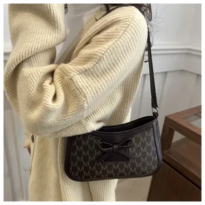 Detail of dark brown retro shoulder bag with M-logo print and leather bow detail