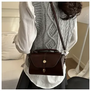 Detail of dark brown vintage crossbody bag with flap cover and metallic round buckle