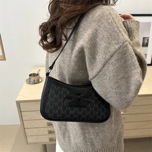 French retro black underarm bag with jacquard M-pattern and bow detail on a model