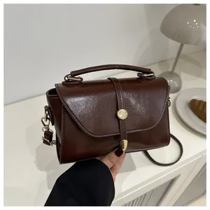 Detailed close-up of dark brown PU leather mini bag with gold hardware and top handle