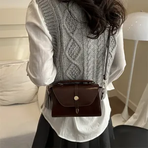 Retro dark brown crossbody bag with top handle and gold clasp shown on a model