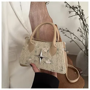 Detailed embroidery and silver star charm on a beige woven straw handbag for women