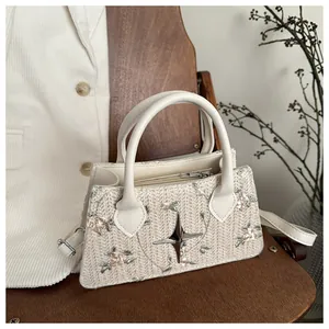 Detailed close-up of woven cream handbag with floral embroidery and star emblem