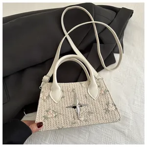Close-up of cream woven bag featuring floral embroidery and silver star hardware