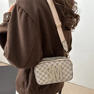 Classic beige monogram camera bag with wide strap worn by model in a street style view