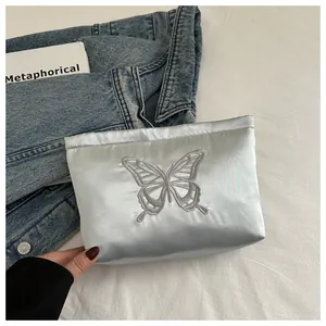 Close-up of elegant butterfly embroidery on light blue satin storage bag with silk texture