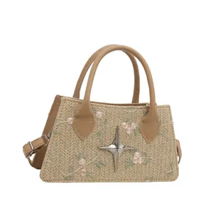 Fashion woven straw tote with floral embroidery and adjustable leather strap on white background