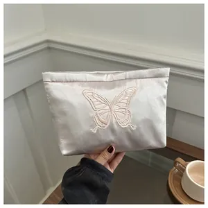 Close-up of champagne satin evening clutch featuring intricate butterfly embroidery detail