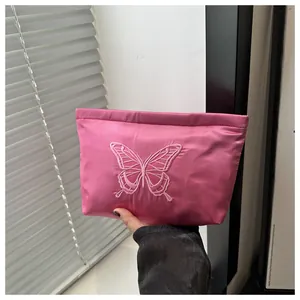 Detail of pink satin evening bag featuring intricate butterfly embroidery and silk texture
