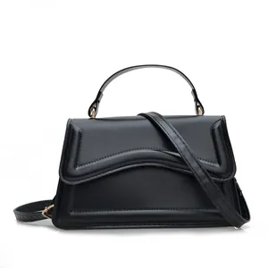 Minimalist black trapezoid shoulder bag with wave embossed flap and gold hardware