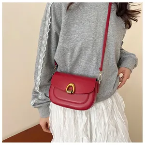 Detail view of red saddle bag featuring a stylish gold U-shaped metal buckle and matte texture