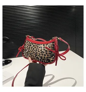 Detail shot of leopard print handbag featuring red patent leather bows and metal rivets