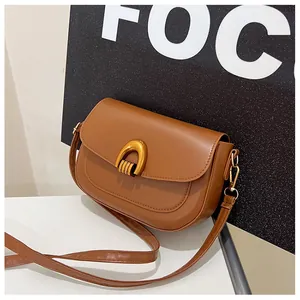 Detailed shot of brown saddle bag featuring a distinctive golden horseshoe buckle