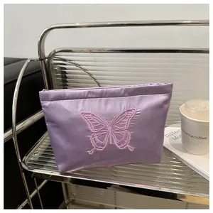 Detail of lavender satin makeup bag featuring pink butterfly embroidery and top zipper