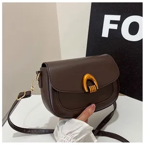 Macro shot of dark brown saddle bag featuring a distinctive gold horseshoe buckle detail