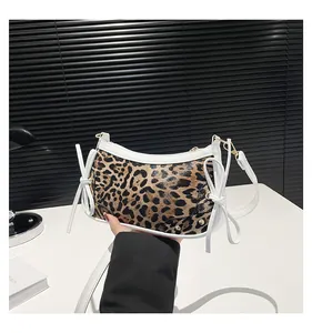 Detail of leopard print handbag with white leather bows and elegant gold hardware
