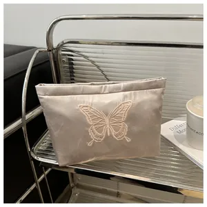 Detail of elegant butterfly embroidery on satin makeup bag with a soft metallic luster