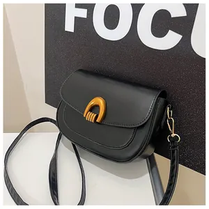 Detail of a black matte saddle bag featuring a golden horseshoe metal buckle and leather strap