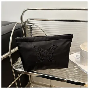 Close-up of black satin clutch with elegant tone-on-tone butterfly embroidery detail