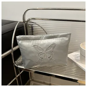 Detailed view of grey satin clutch with elegant butterfly embroidery on glossy fabric