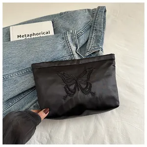 Detail of elegant black satin clutch featuring exquisite butterfly embroidery on fabric